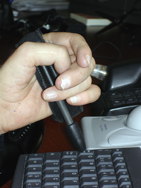The user's hand with the writing stick attached. The palm of the hand is visible, where the stick is attached to the universal band. 