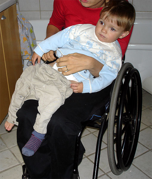 Child sits on user's lap; user pulls on pants