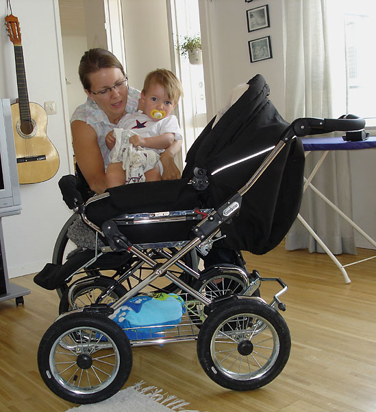 User sits next to stroller; stroller and wheelchair are same height