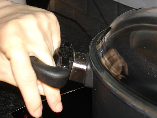 The user grabs the pot by inserting the middle finger into the handle.