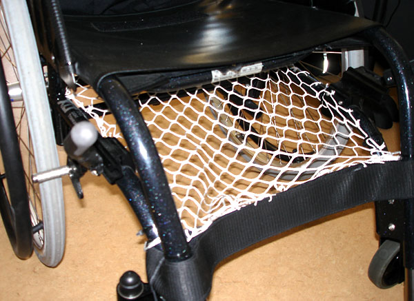 Net attached to wheelchair frame under seat