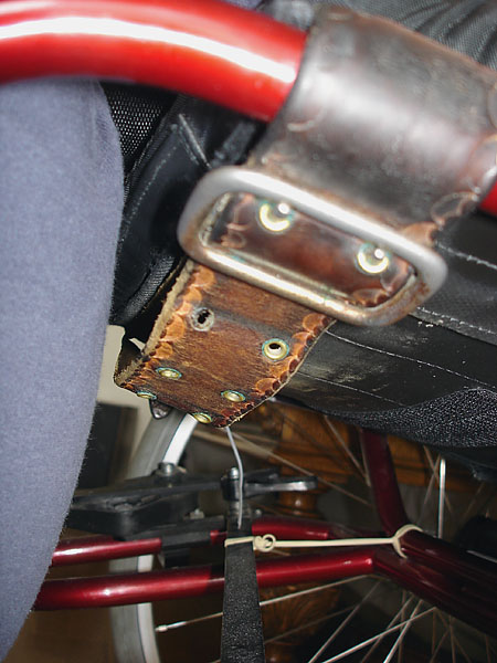 Leather strap around wheelchair frame on front of seat