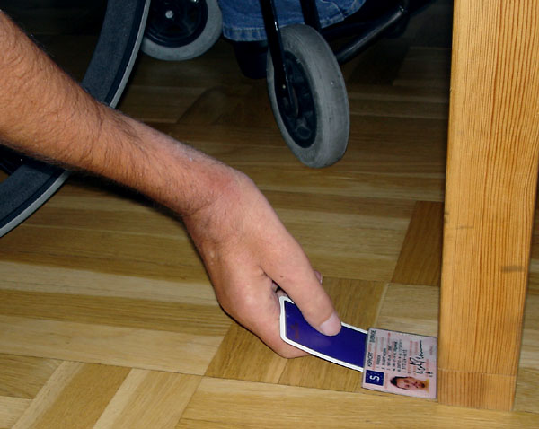 User uses playing card to manipulate driving licence against table leg