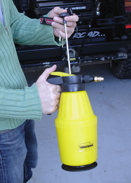A person pumps air into the pressure sprayer.