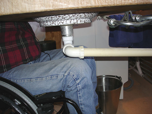 User at washbasin; knees have room under drainpipe