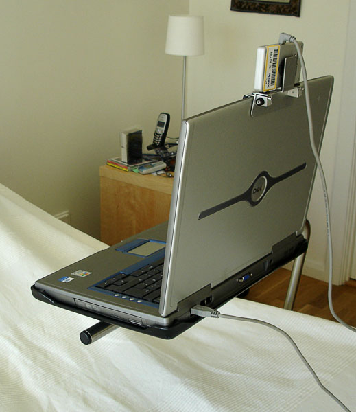 Laptop med huvudmus på specialbord på stativ ovanför sängen