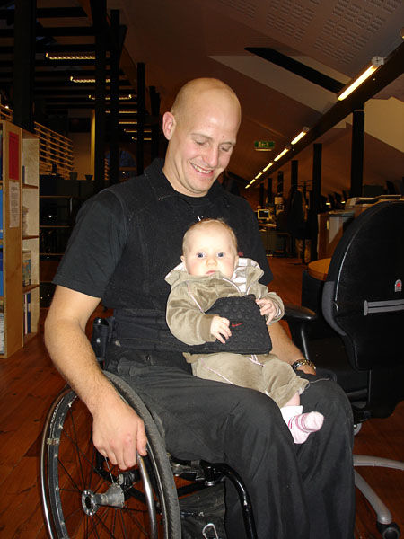 User with daughter on lap with a soft corset around him and the child