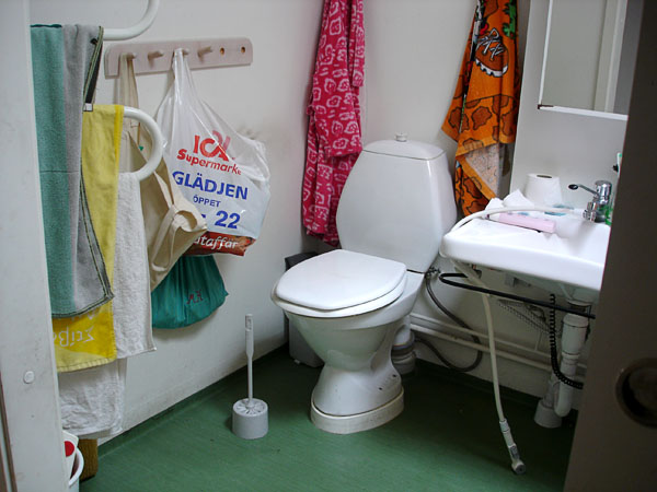 Badrum med förhöjd toalettstol och skjutdörr