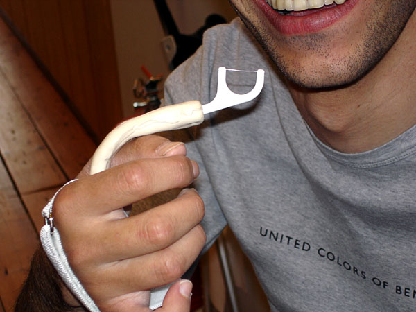 Användaren med anpassad tandtrådshållaren i universalband. Tandtrådsbygel är vänd uppåt.