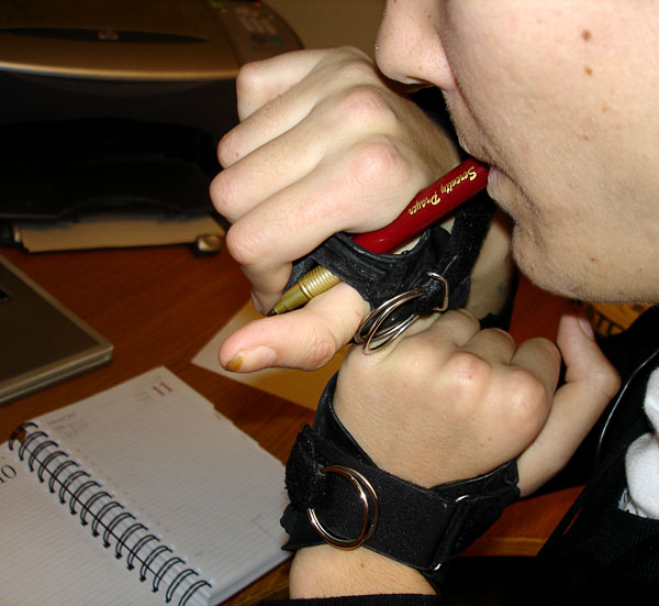 User fastens pen to wheelchair glove