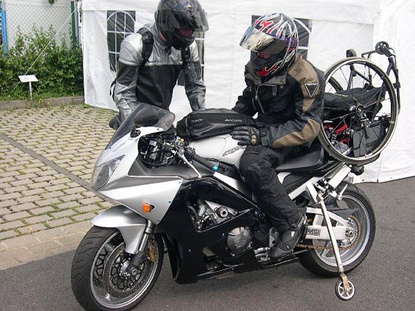 Användaren på motorcykeln med stödhjulen nerfällda, rullstolen på pakethållaren. Foto: från www.kritto.se