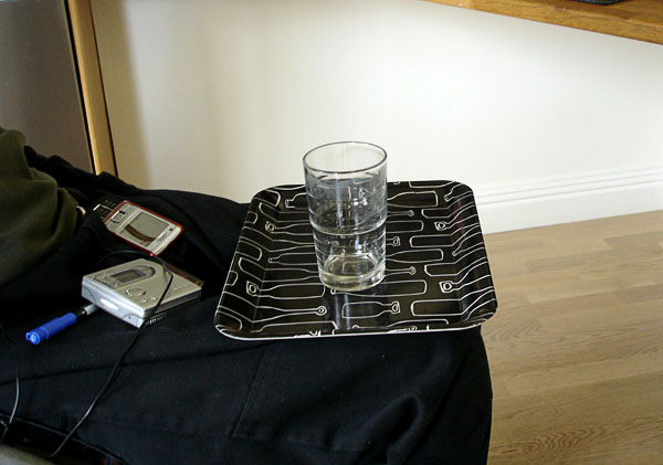User transports glass of water on tray on lap