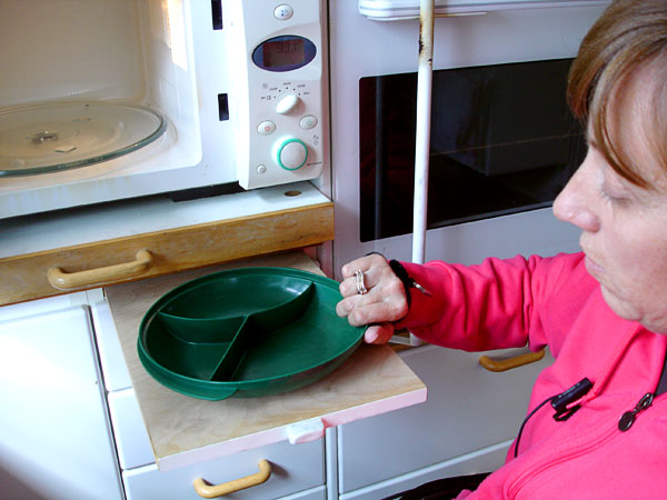 The user moves the dish from the microwave to the sliding board