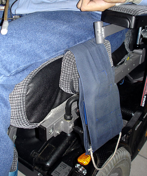Fabric bag with remote control units hanging on wheelchair.