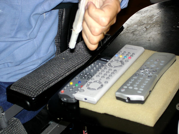 User next to table with control units for TV, etc placed on a piece of foam rubber