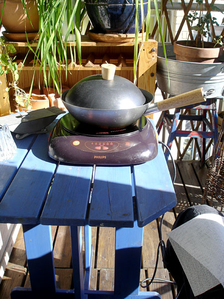 Elektrisk kokplatta och wok på balkongbordet