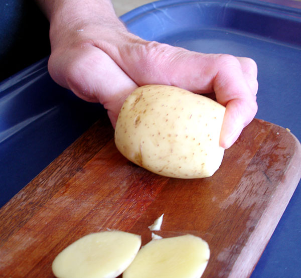  Användaren håller i en potatis med avskurna kanter 