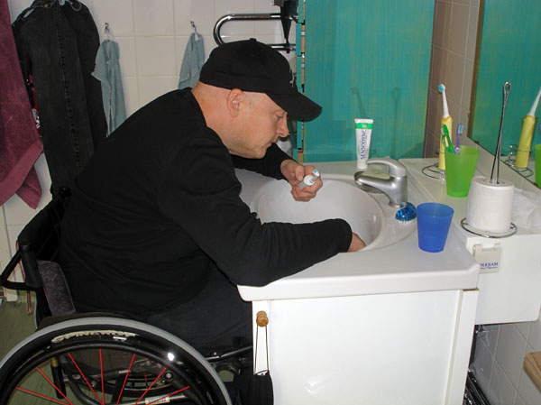 User leans with elbows on washbasin for balance