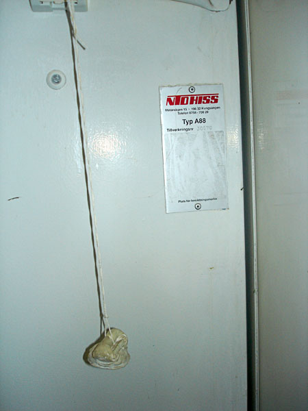 Hissöppnare hängande på ett snöre i hissen