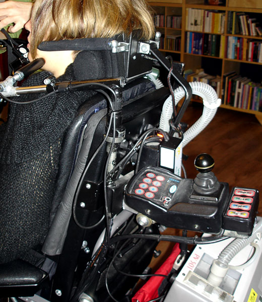 Vårdarstyrning monterad på baksidan av rullstolens ryggstöd