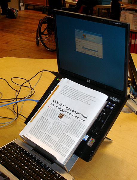 Computer placed on laptop support and newspaper on manuscript holder