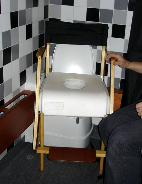 Shower chair with soft back, wooden armrest, padded seat with opening on the toilet seat.