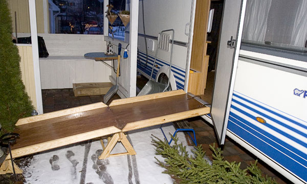 RV with two-piece carved wooden ramp at the door.