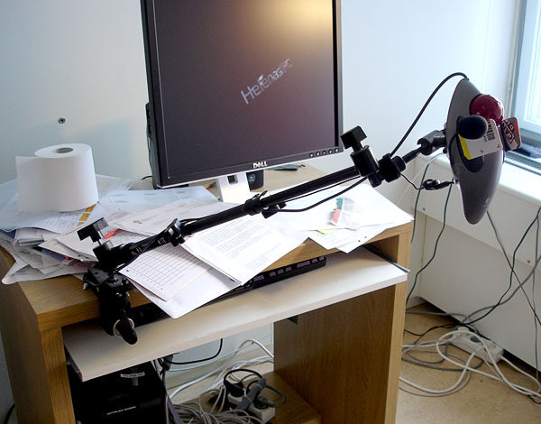 Computer workstation with a trackball mouse on a long table mount, adjustable in several joints.