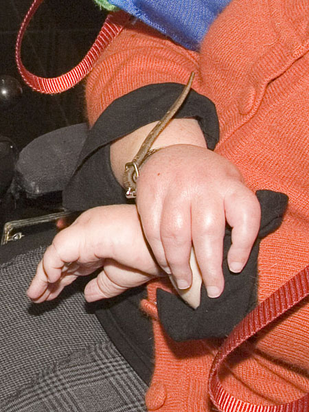 Helena's crossed hands, held together with a leather strap..