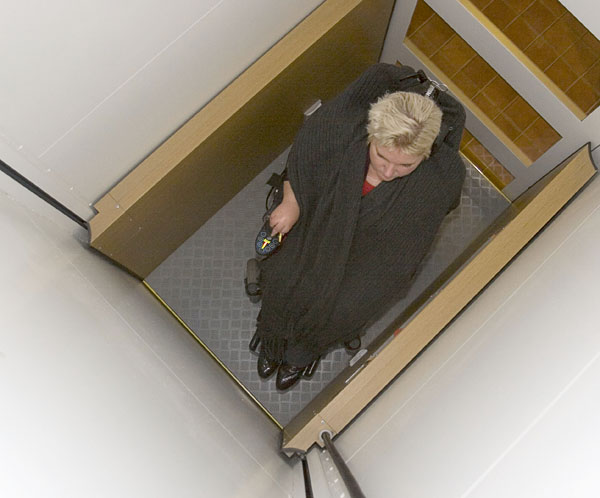 Helena in elevator; she presses elevator button with front wheel