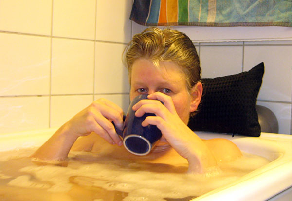 User in bathtub with a cup of coffee