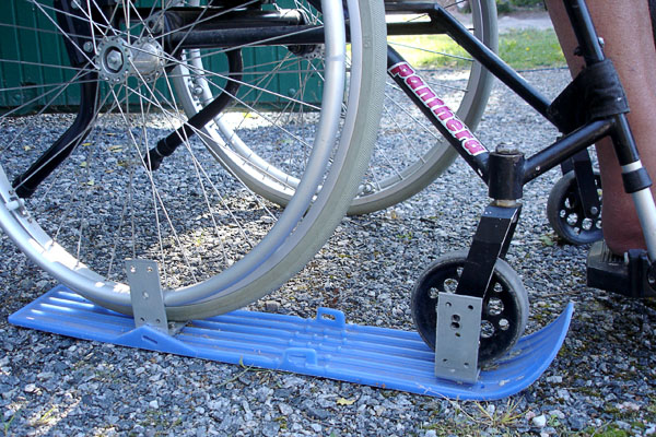 Plastic skis attached under the wheelchair