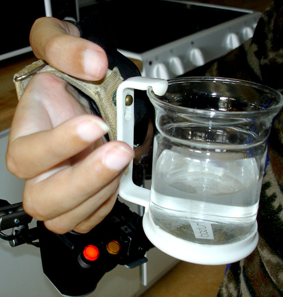 The user holds the cup (the handle of the cup is hooked onto the screws of the universal strap) 