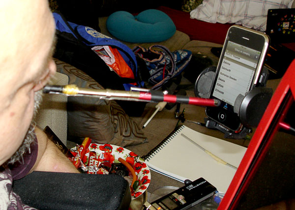 In front of the user is his iPhone on a stand, he controls the iPhone with a mouth stick.
