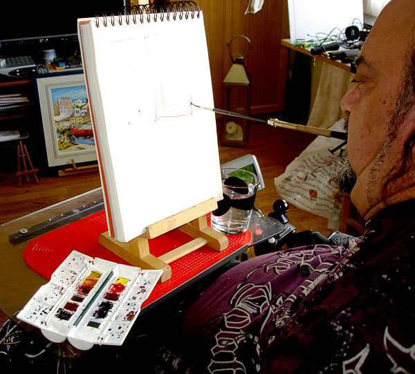 The user paints by mouth with the brush in the pen extension.