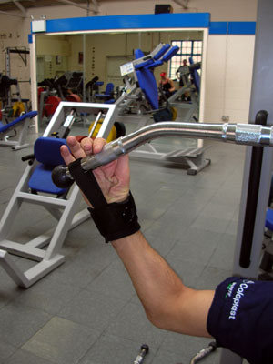 Användaren i gymmet med grepphjälpmedel för träningsredskap. Foto: www.activehands.co.uk