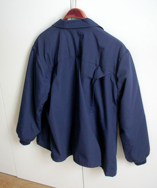 Windbreaker from the back. The two backparts overlap, it is not visible that the back is open..