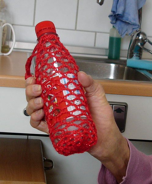 Användaren håller i en flaska med virkat överdrag.