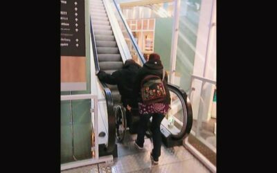 Åka uppför en rulltrappa med rullstol med hjälp