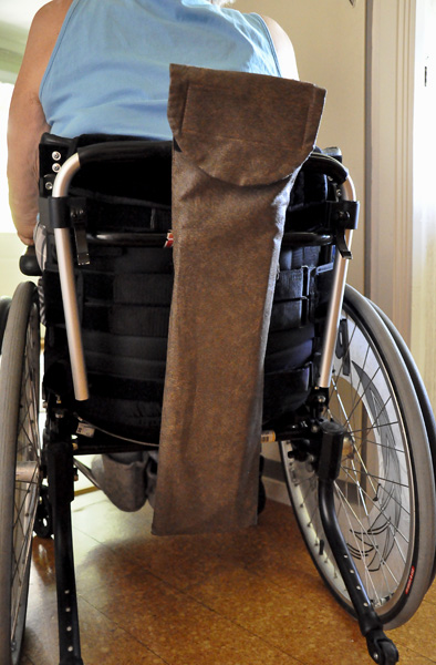 Väska med glidbräda, fastsatt på användarens rullstol. 