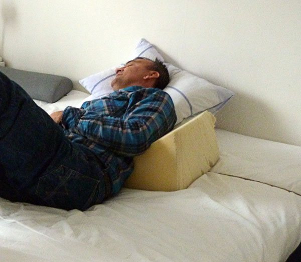 User lying on side in bed with wedge cushion