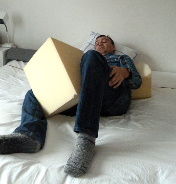 User in bed with foam cushion between knees