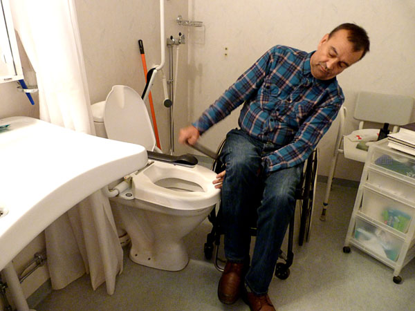 User transfers to the toilet using a sliding board