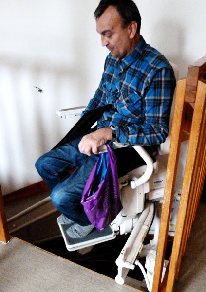 User on stairlift with "emergency bag"