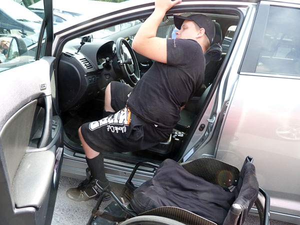 Användaren sittande på bilens inbyggda glidbräda under förflyttning in i bilen