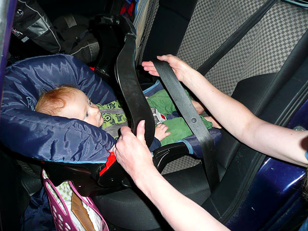 Förälder placerar babyskyddet rätt på sätet och sätter säkerhetsbältet på plats