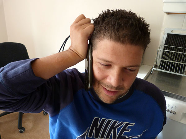 User holds the phone against his ear with the help of key ring attached to the phone string