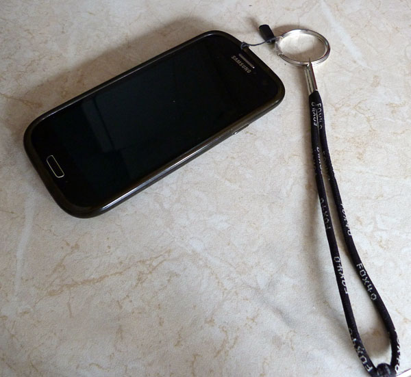 A key ring with a loop of string is attached to a phone.