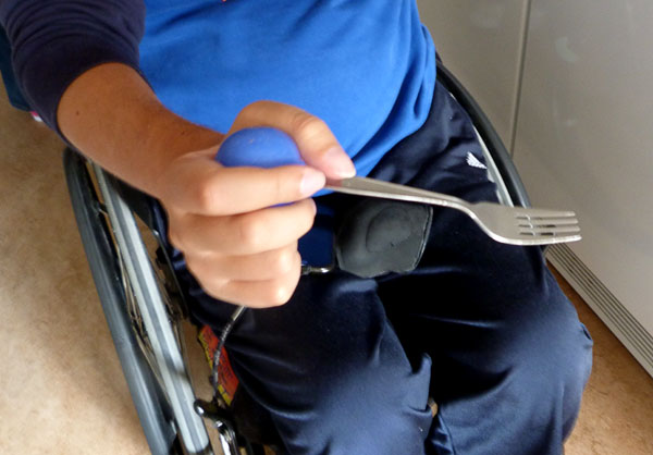 A fork sits in a silicone ball, which the user holds in his hand.