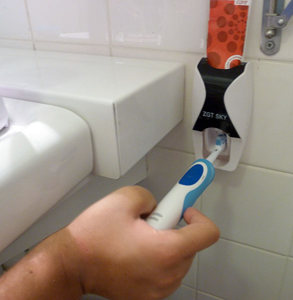 Användaren håller tandborsten mot tandkrämsdispensern